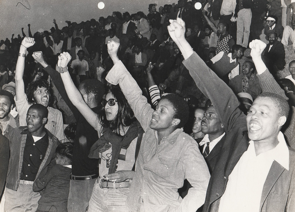 Vino Reddy (née Pillay) in dark glasses during the Viva FRELIMO rally, photograph taken outside of the Curries Fountain Stadium in Durban, 25 September 1974. Source: Vino Reddy