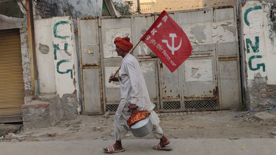 A farmer at the protest encampment at Delhi’s Singhu Border carries the flag of the All India Kisan Sabha, 21 November 2021. Subin Dennis / Tricontinental: Institute for Social Research